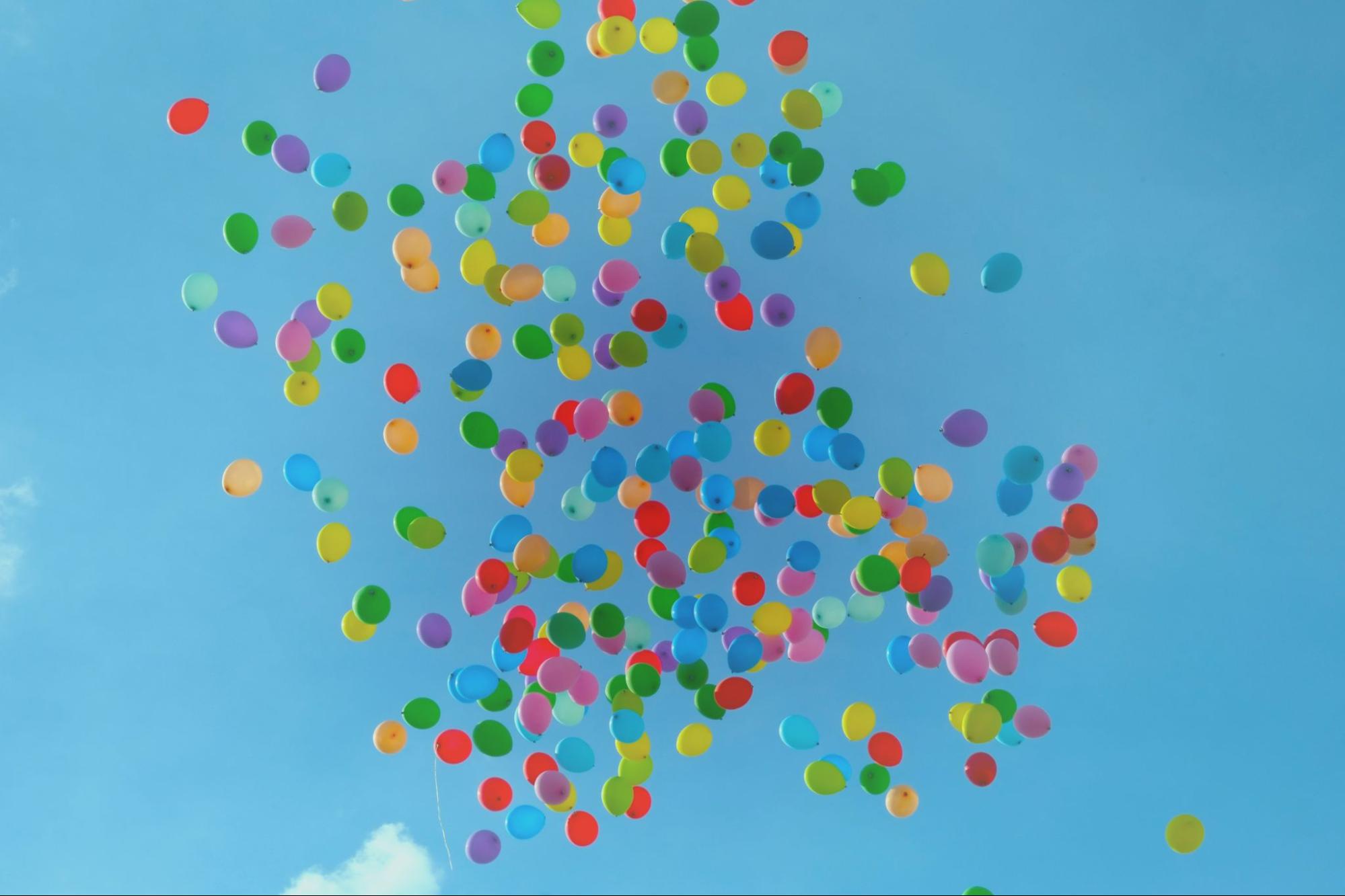 Plakat z balonami które unoszą się w niebo.
